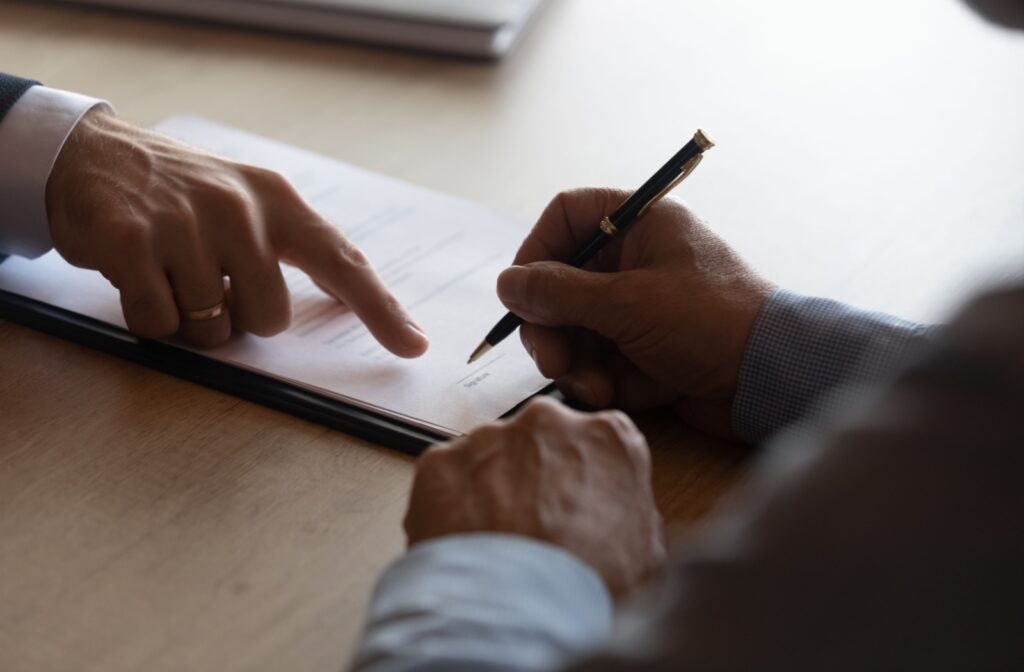 A close up of an older man's hand signing legal documents. 