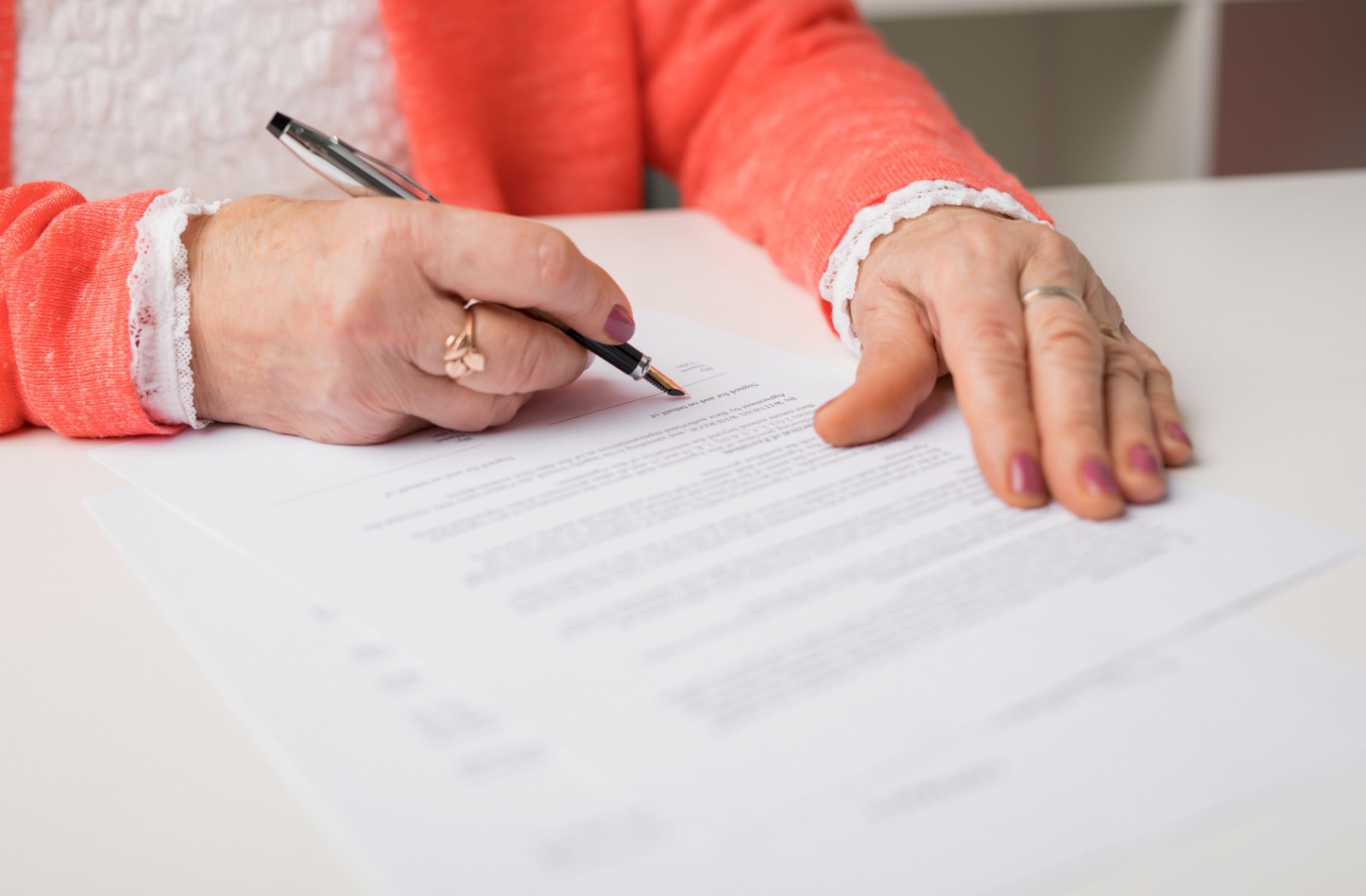 Close-up of a senior's hands as they sign a legal document.