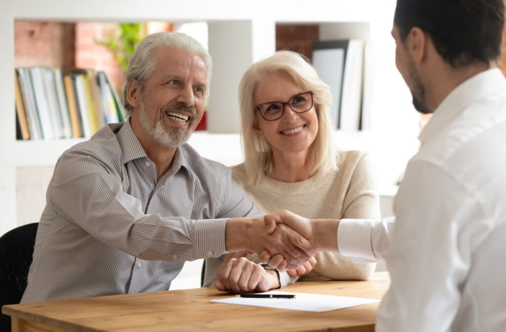 A senior couple shakes hands with a lawyer after discussing legal matters.