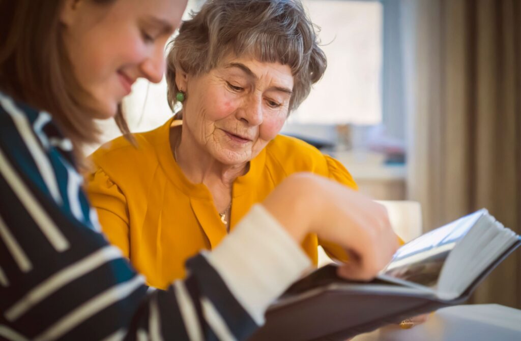 A senior woman and her daughter look at a photo album together.