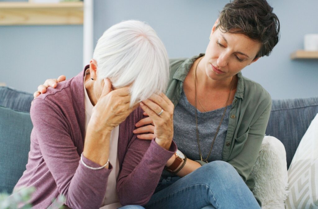 A daughter comforting her elderly mother, who is experiencing confusion and frustration from dementia.