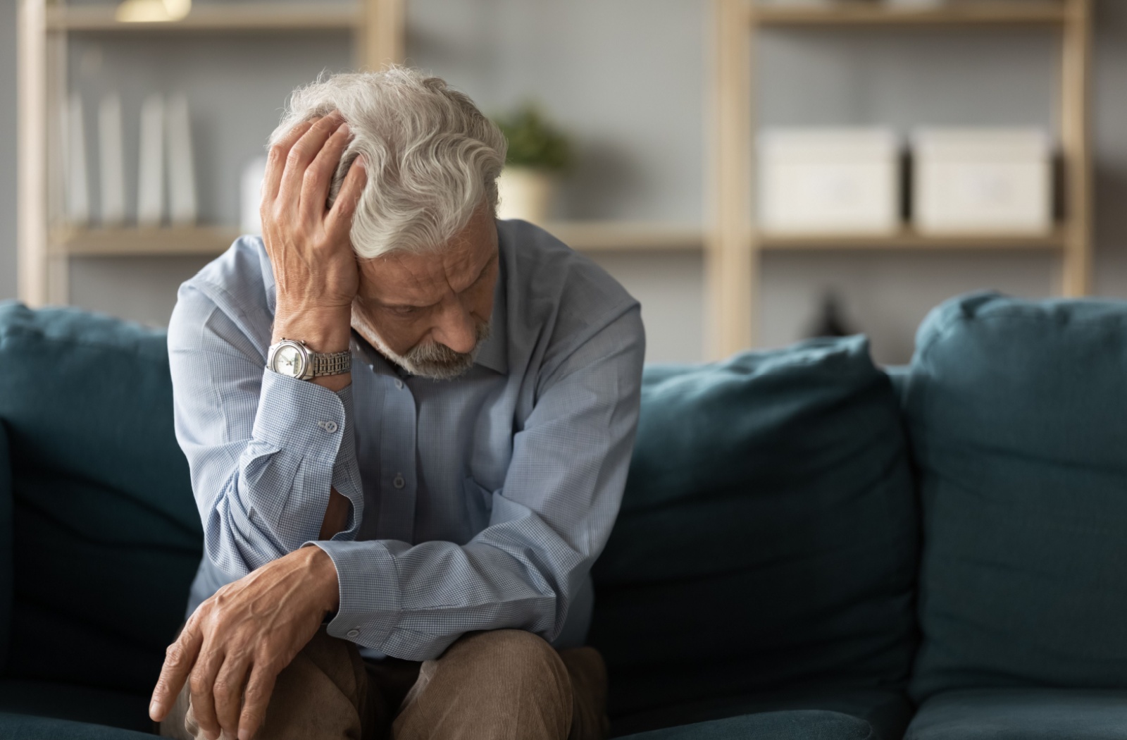 an older person holding their head indicating a bout of forgetfulness.