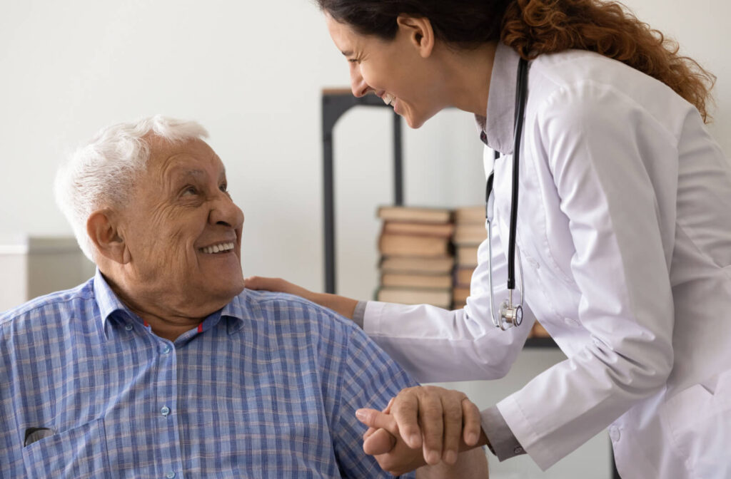 An older adult with dementia smiling up at a caregiver during a speech therapy exercise in memory care.