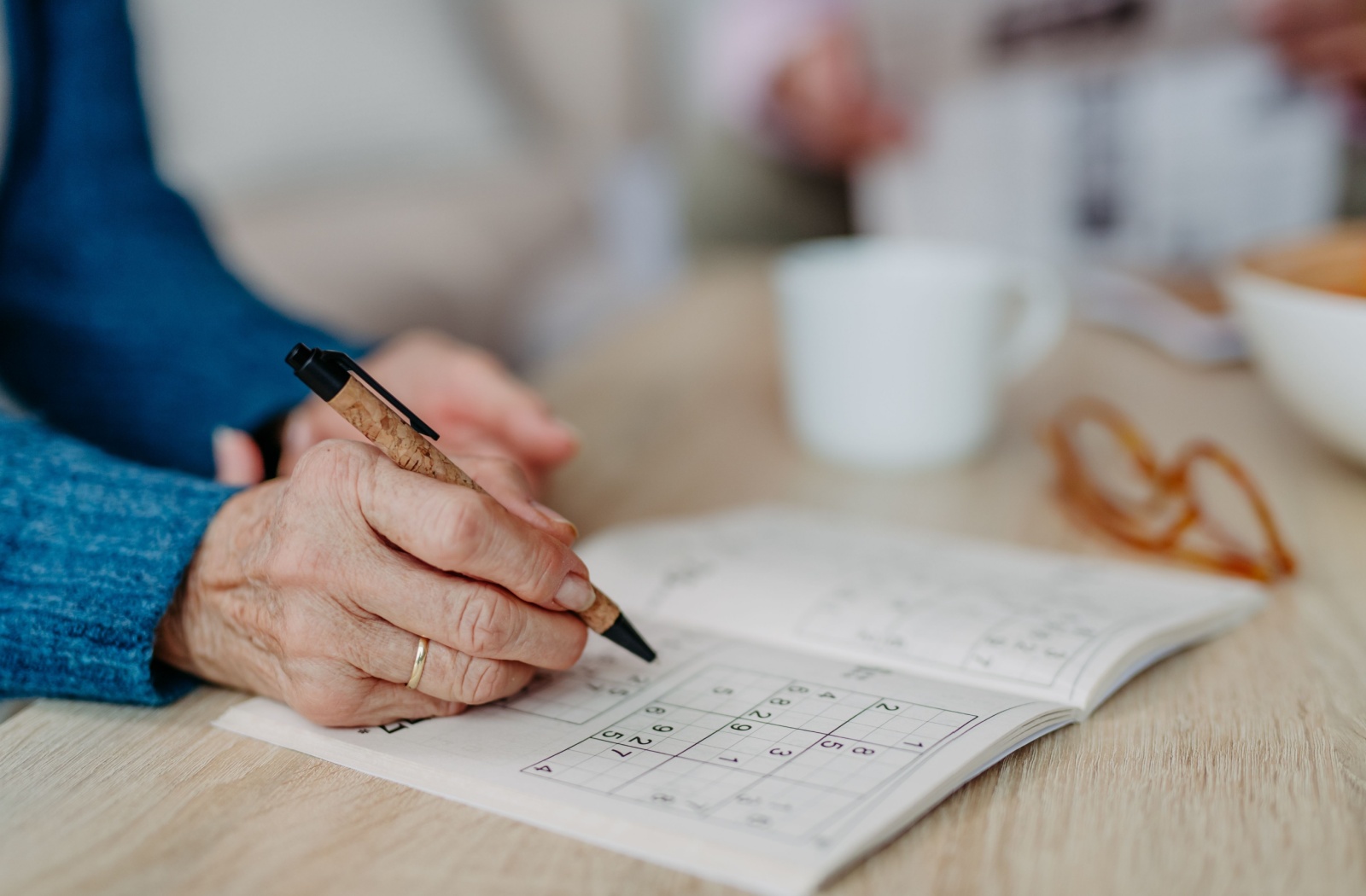 A close-up image of an older adult's hand as they do a Sudoko memory puzzle.