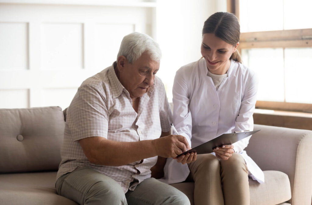 A smiling caregiver in memory care shows a resident a clipboard and explains the basics of a legal document
